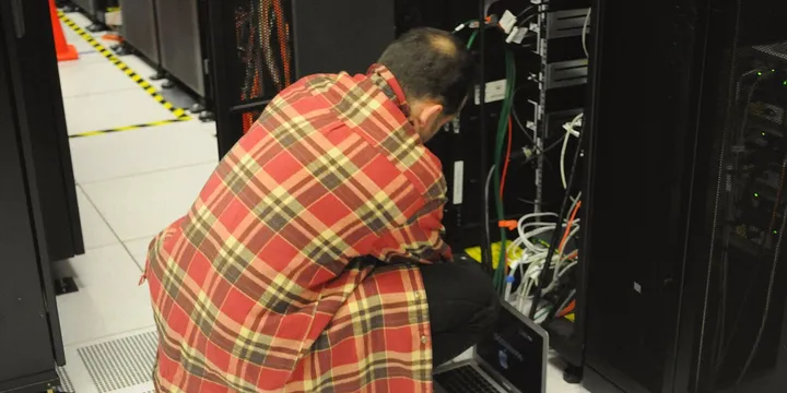Technician with a laptop working on a server rack at NERSC